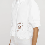 side view of woman in white eyelet shirt on white background 