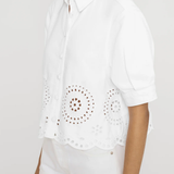 side view of woman in white eyelet shirt on white background 
