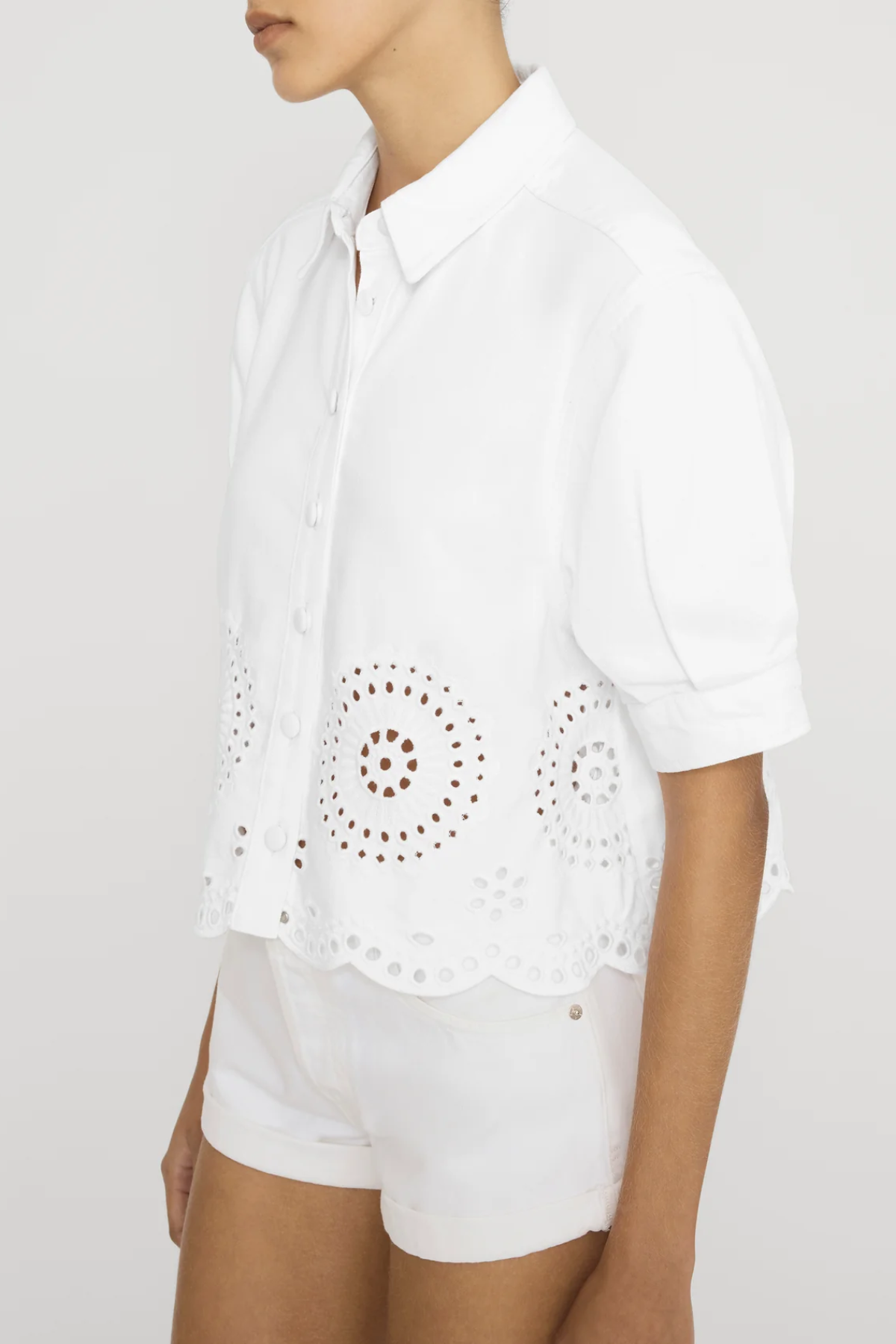 side view of woman in white eyelet shirt on white background 