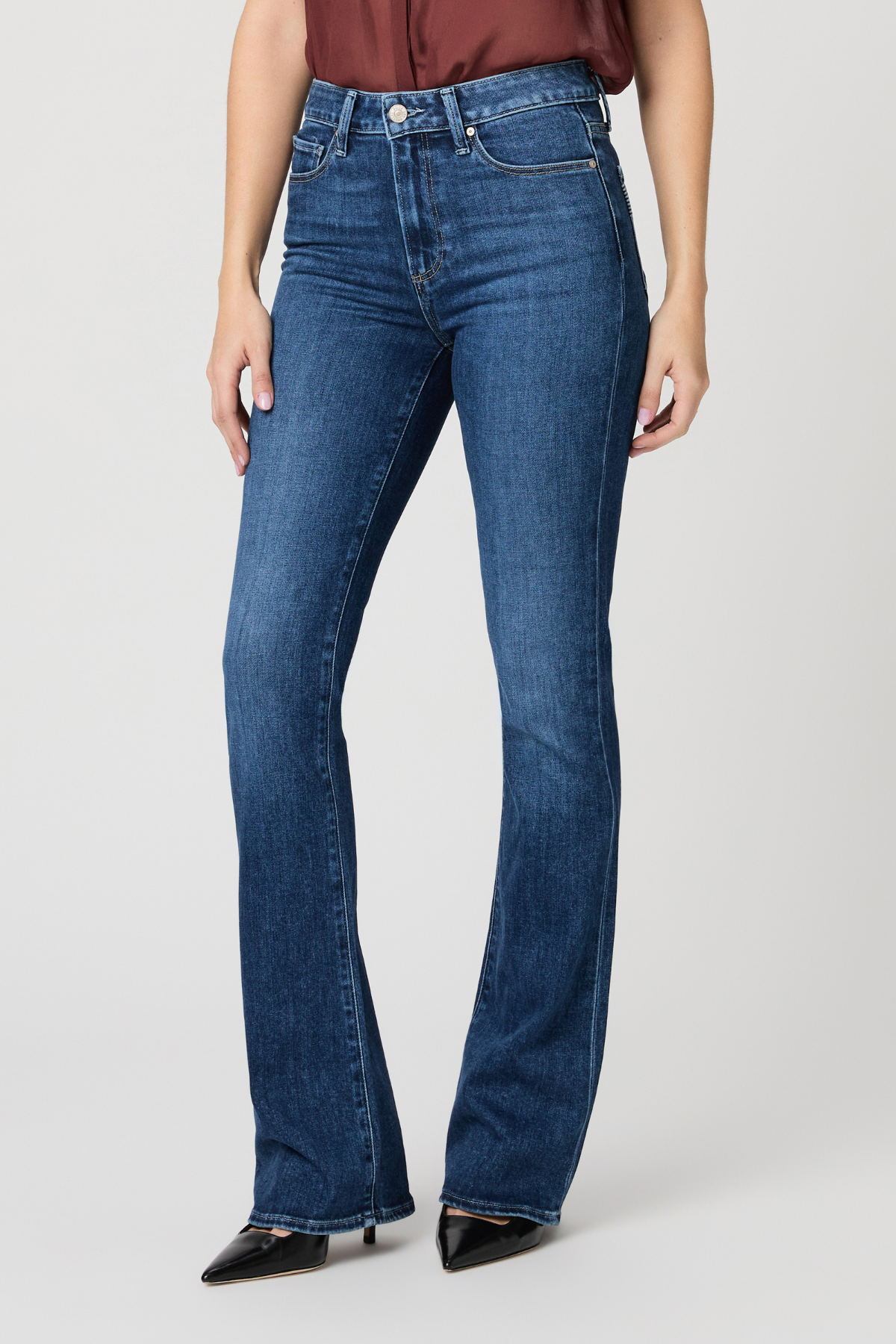 Person wearing blue jeans on a plain background