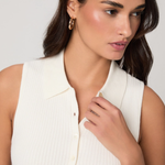 Woman wearing a white sleeveless top against a plain background