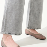 Person wearing gray jeans and pink flats on a white background