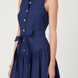 A sleeveless navy blue midi dress with a high collar, button-front bodice, matching tie belt, and lace trim details, shown on a model against a light gray background.