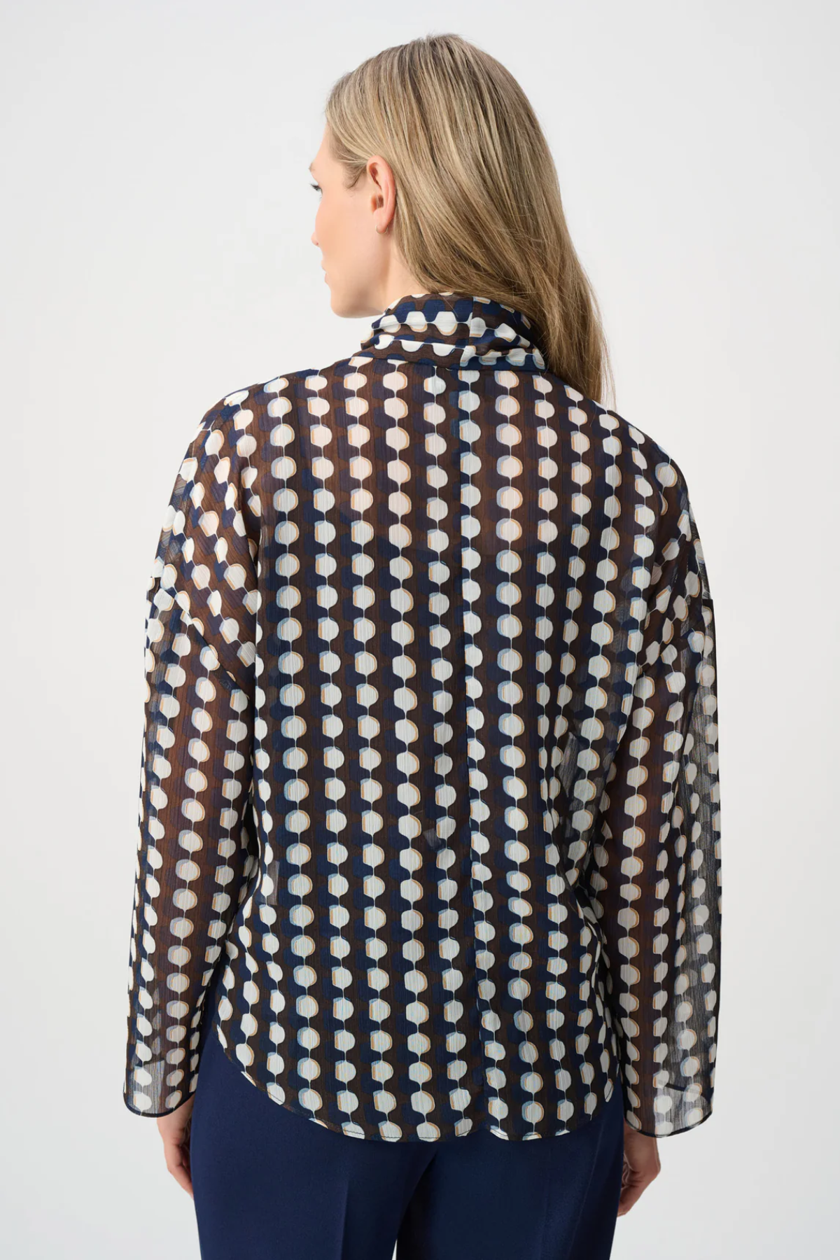 Model wearing a long-sleeve chiffon blouse with a geometric print and tie-neck detail in a relaxed, feminine silhouette.