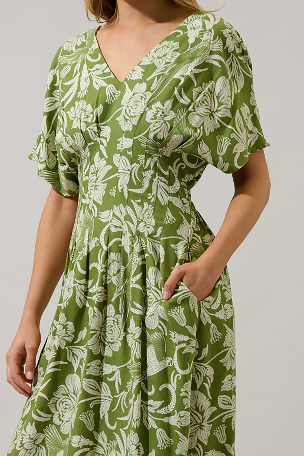 Green floral dress worn by a person on a plain background