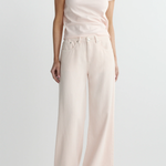 Person wearing a white t-shirt and light pink wide-leg pants on a plain background