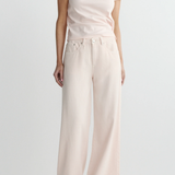 Person wearing a white t-shirt and light pink wide-leg pants on a plain background