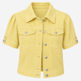 A light yellow cropped denim jacket with puff sleeves, silver-tone buttons, and flap chest pockets, shown on a plain light gray background.
