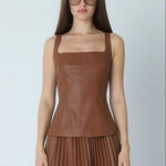 A woman modeling a brown faux-leather sleeveless top with a square neckline and matching pleated skirt against a light gray background.