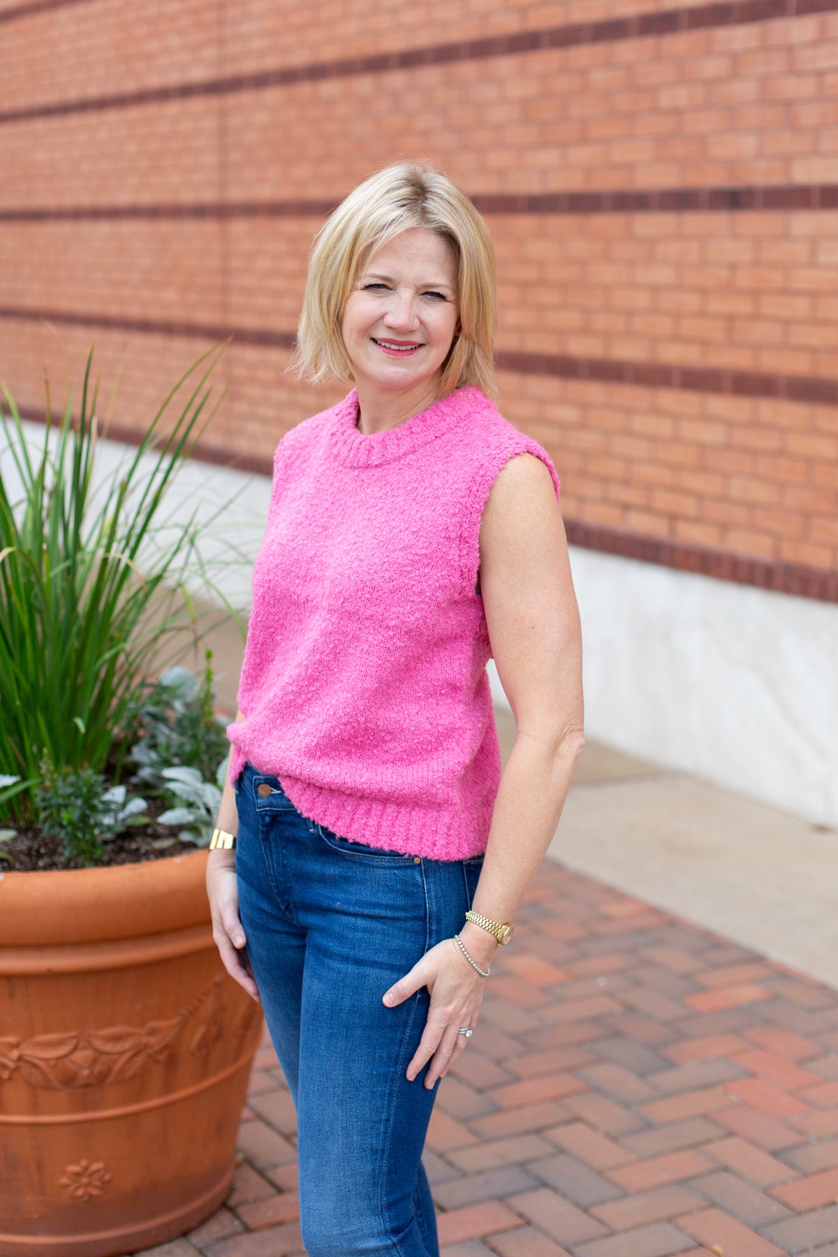 Sleeveless crew neck knit sweater styled with neutral bottoms.