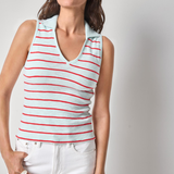 Woman wearing a striped tank top and white pants against a plain background