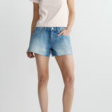 Person wearing a light pink t-shirt and denim shorts on a white background