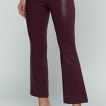 A model wearing dark burgundy faux-leather cropped flare pants with a silver button closure, paired with dark brown heeled sandals, against a light gray studio background.