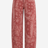 A pair of high-waisted, wide-leg cropped jeans in a washed dusty rose pink denim with a white paisley and floral bandana print, shown against a plain white background.