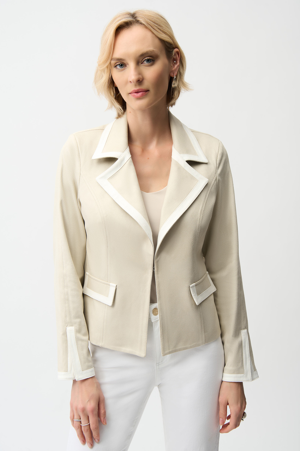 Woman wearing a beige blazer with white trim on a white background