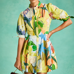 Woman wearing a colorful floral dress against a teal background