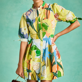 Woman wearing a colorful floral dress against a teal background