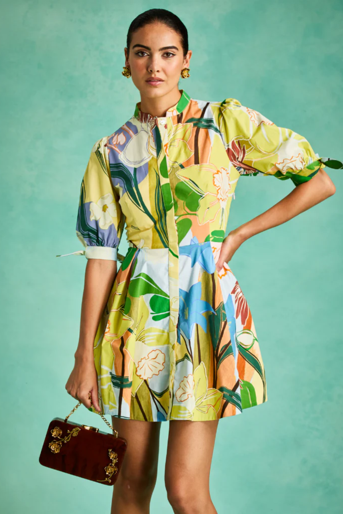 Woman wearing a colorful floral dress against a teal background