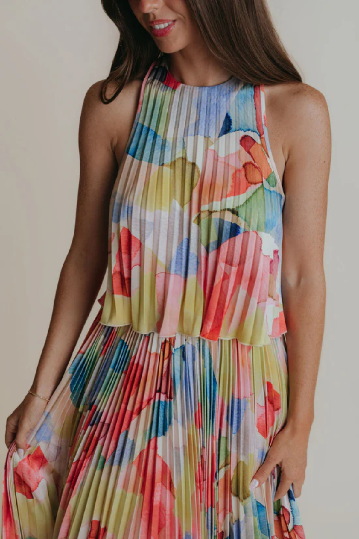 Woman wearing a colorful floral dress against a neutral background