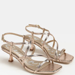 Pair of gold strappy high-heeled sandals on a white background