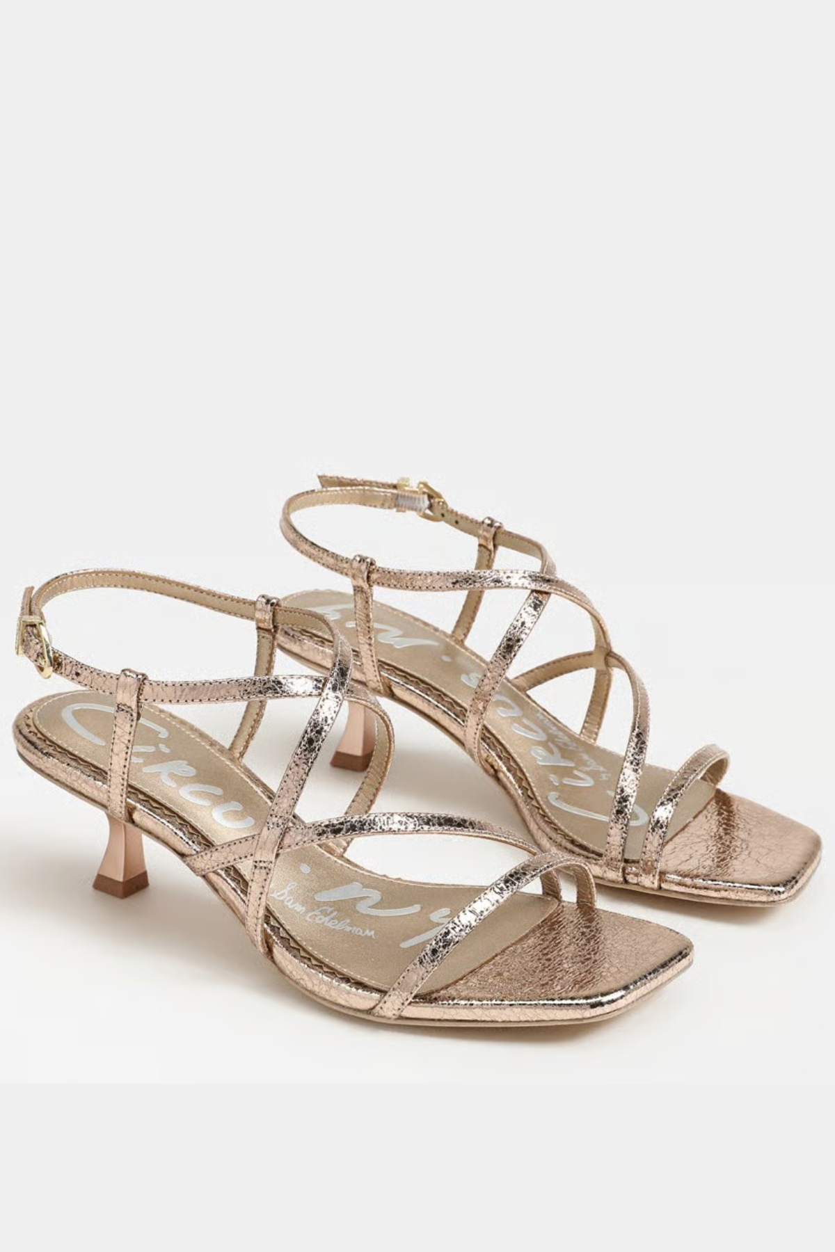 Pair of gold strappy high-heeled sandals on a white background