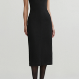 Model wearing black midi dress on an off white background.