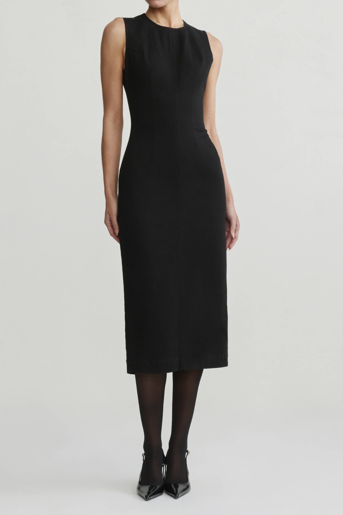Model wearing black midi dress on an off white background.