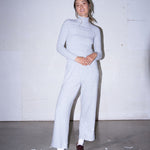 Woman wearing light grey knit pants with a straight leg silhouette, styled in soft studio lighting.