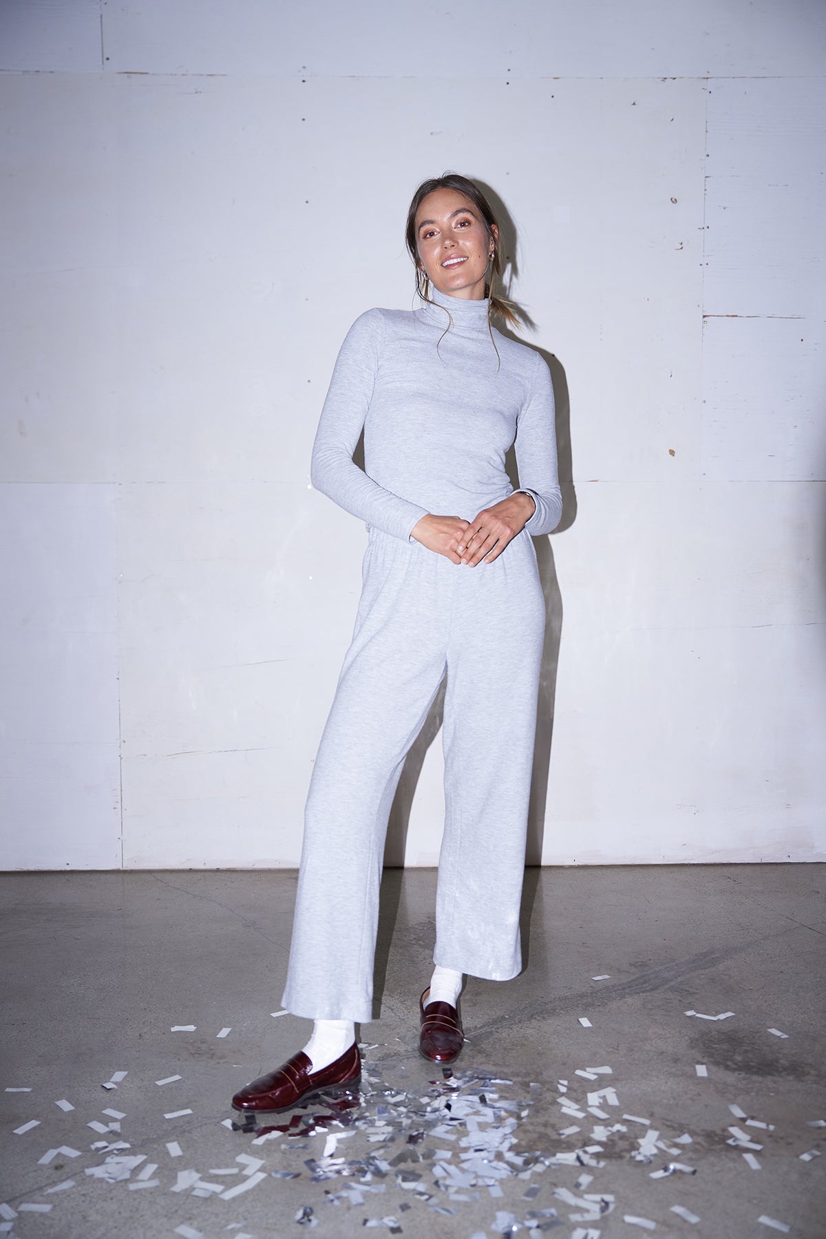 Woman wearing light grey knit pants with a straight leg silhouette, styled in soft studio lighting.