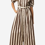 A woman wearing a brown and cream vertical striped midi shirt dress with puff sleeves, a button-up front, and a matching belt, paired with brown heeled sandals against a light gray background.