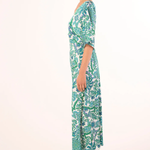 Woman wearing a green and white patterned dress on a white background