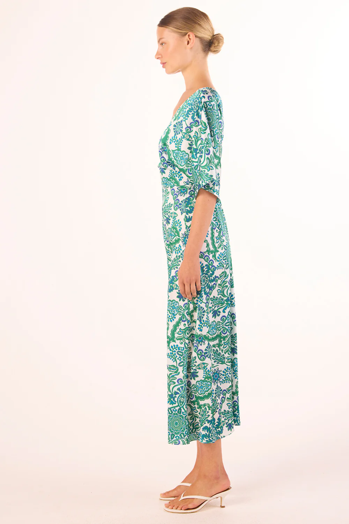 Woman wearing a green and white patterned dress on a white background