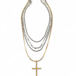 Stack of layered necklaces with a cross pendant on a white background
