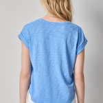 Woman wearing a blue t-shirt and white pants on a gray background
