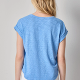 Woman wearing a blue t-shirt and white pants on a gray background