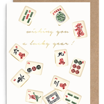A greeting card with a kraft envelope, featuring illustrated mahjong tiles around gold cursive text that reads 'wishing you a lucky year!'.