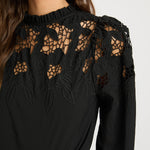 Black lace top worn by a person on a white background