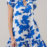 Woman wearing a white dress with blue floral patterns on a plain background
