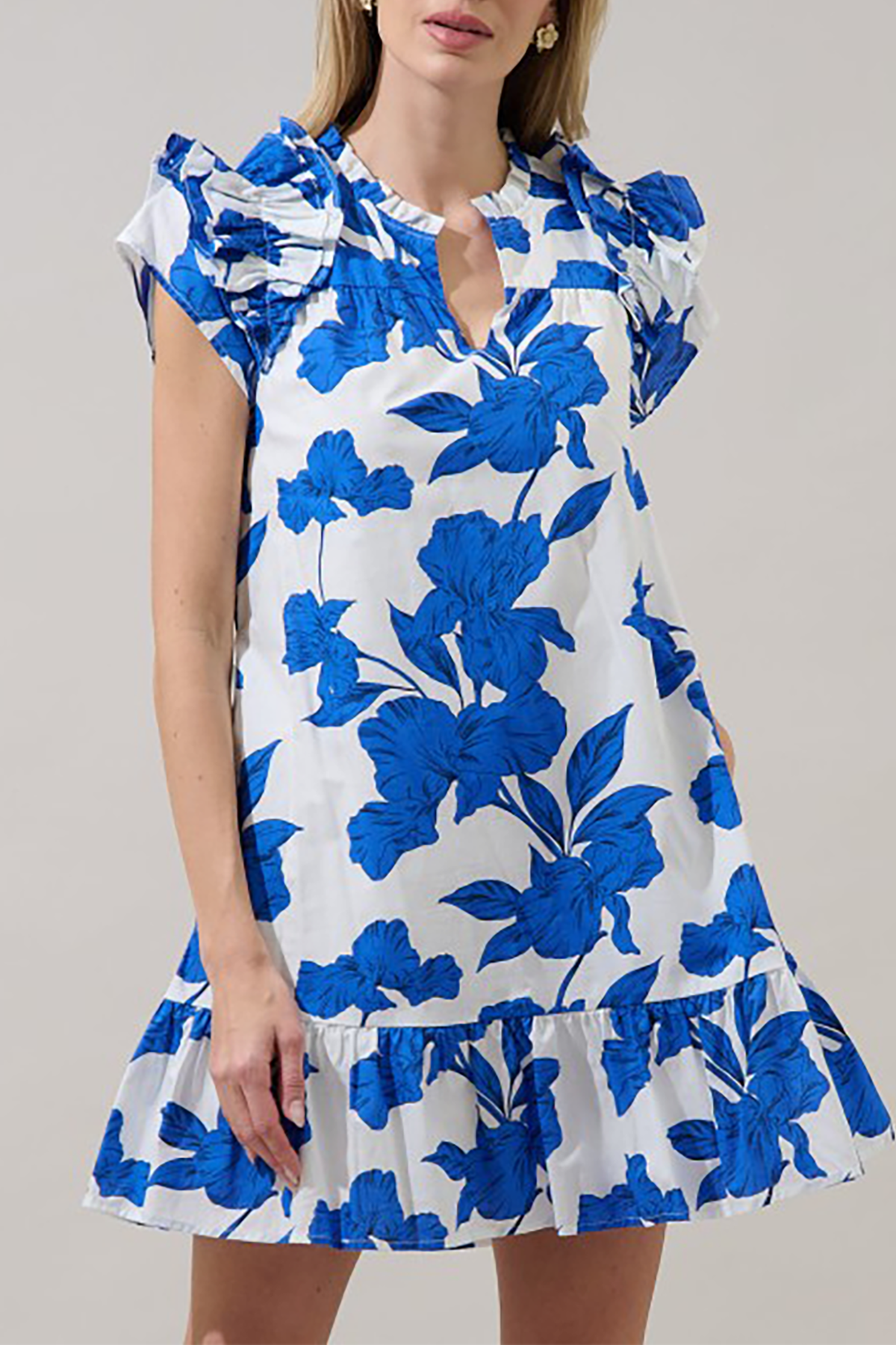 Woman wearing a white dress with blue floral patterns on a plain background