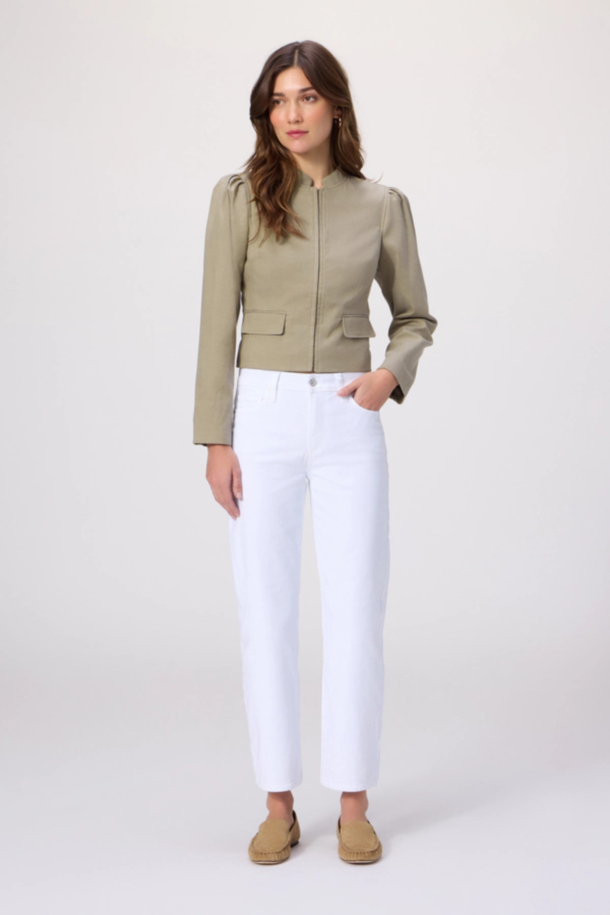 Woman wearing a green jacket and white pants on a white background