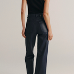A model shown from the back wearing a black sleeveless top and dark navy wide-leg trousers against a light gray studio background.