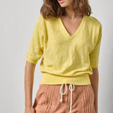 Woman wearing a yellow top and pink shorts on a plain background