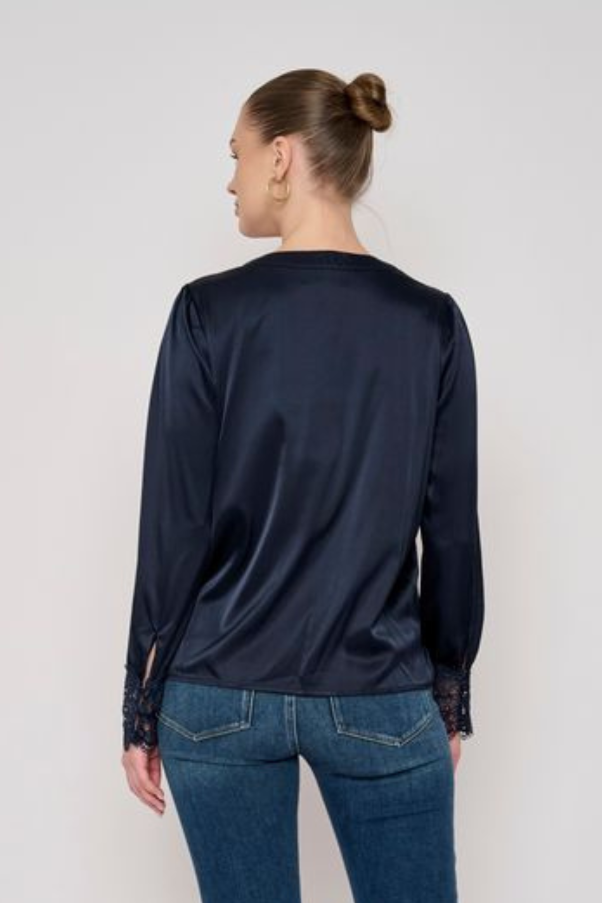 Model wearing a long-sleeve blouse with delicate lace detailing and a flattering tailored silhouette.