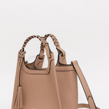 A structured tan leather handbag with braided top handles, a tassel detail, and a detachable shoulder strap, shown on a plain light background.