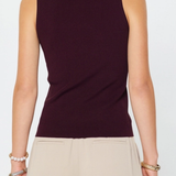 Person wearing a dark purple sleeveless top and beige pants on a white background