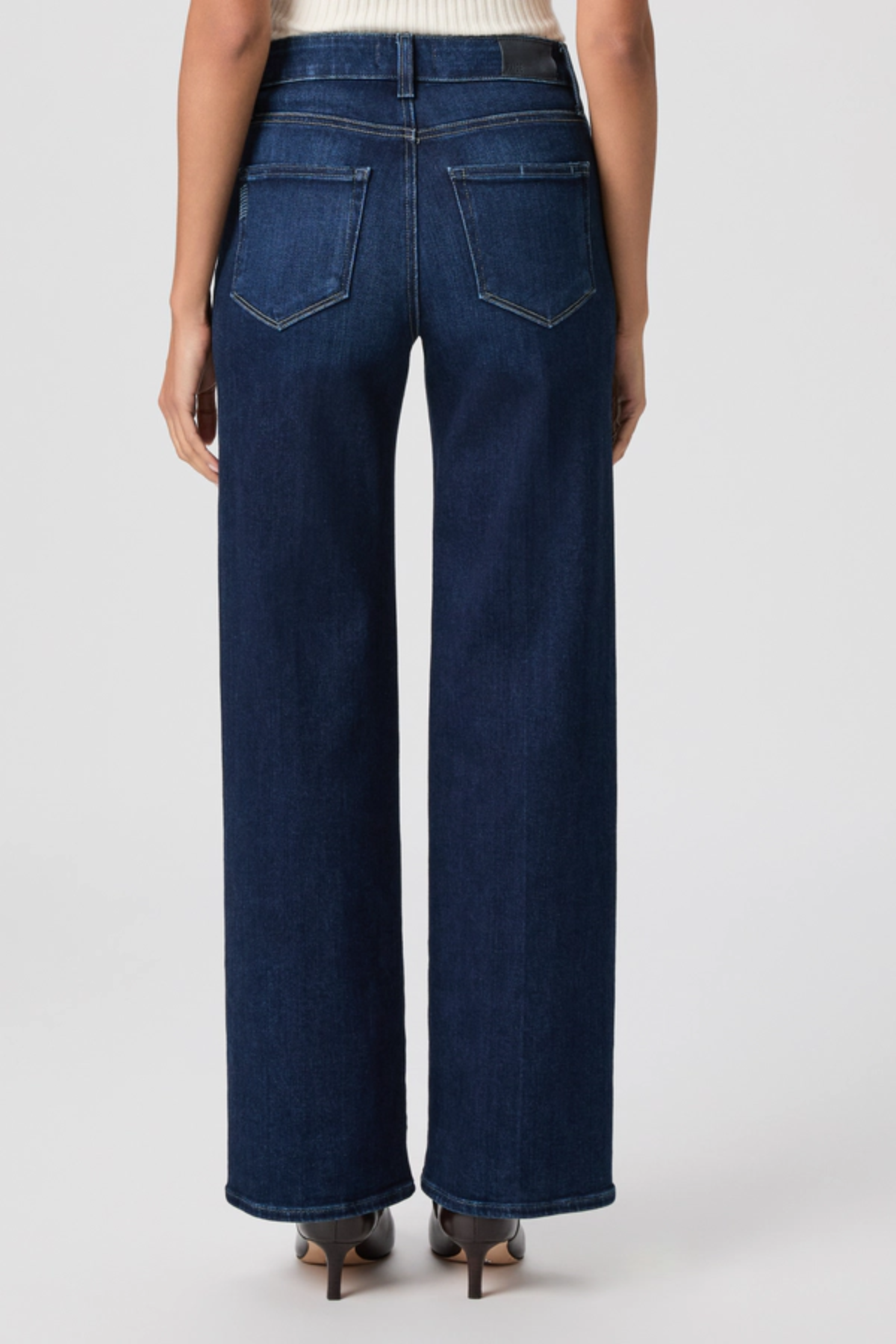 Person wearing dark blue jeans on a white background