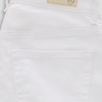 Close-up of the back waistband and pocket area of white denim jeans, showing a beige brand patch with a circular logo.