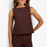 Model wearing a sleeveless fitted top in a solid color with a sleek, minimalist silhouette.