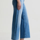 Person wearing light blue jeans on a plain background