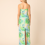 back of woman in printed midi dress on tan background 